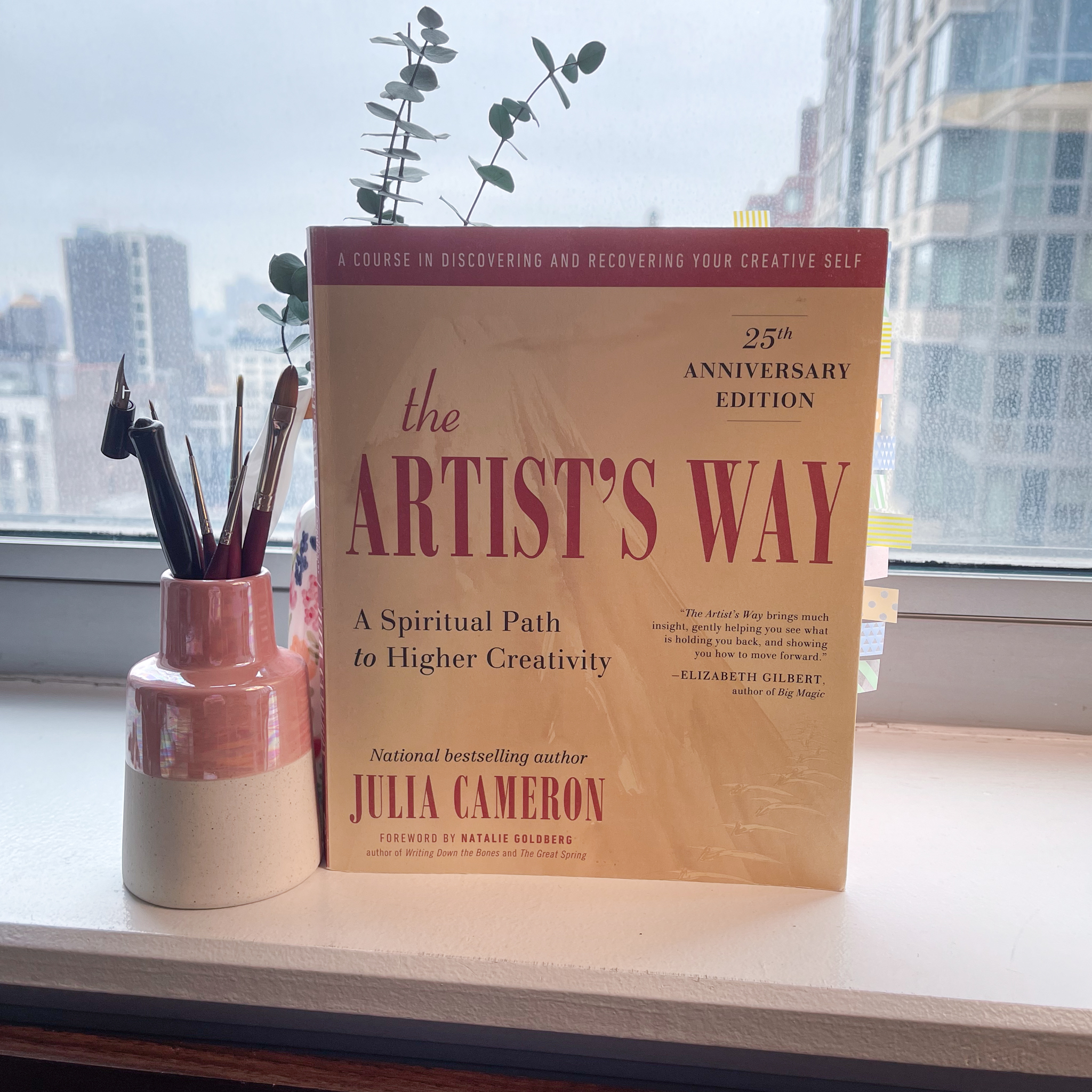 The book "The Artist's Way" standing upright on a desk